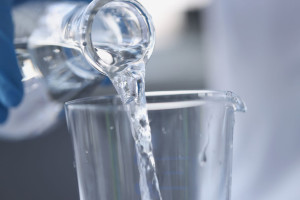 Water is poured from transparent bottle into glass